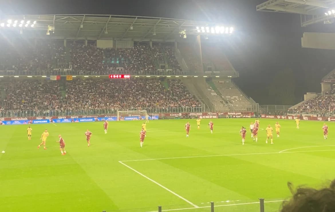 Le stade Saint-Symphorien de nuit, tribunes pleines, pendant le jubilé de Robert Pirès : joueurs en maillot grenat et en maillot jaune sur la pelouse.